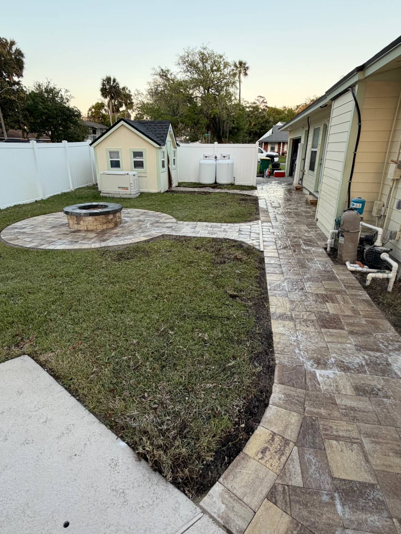 Paver path connecting fire pit patio to side of house with fresh sod