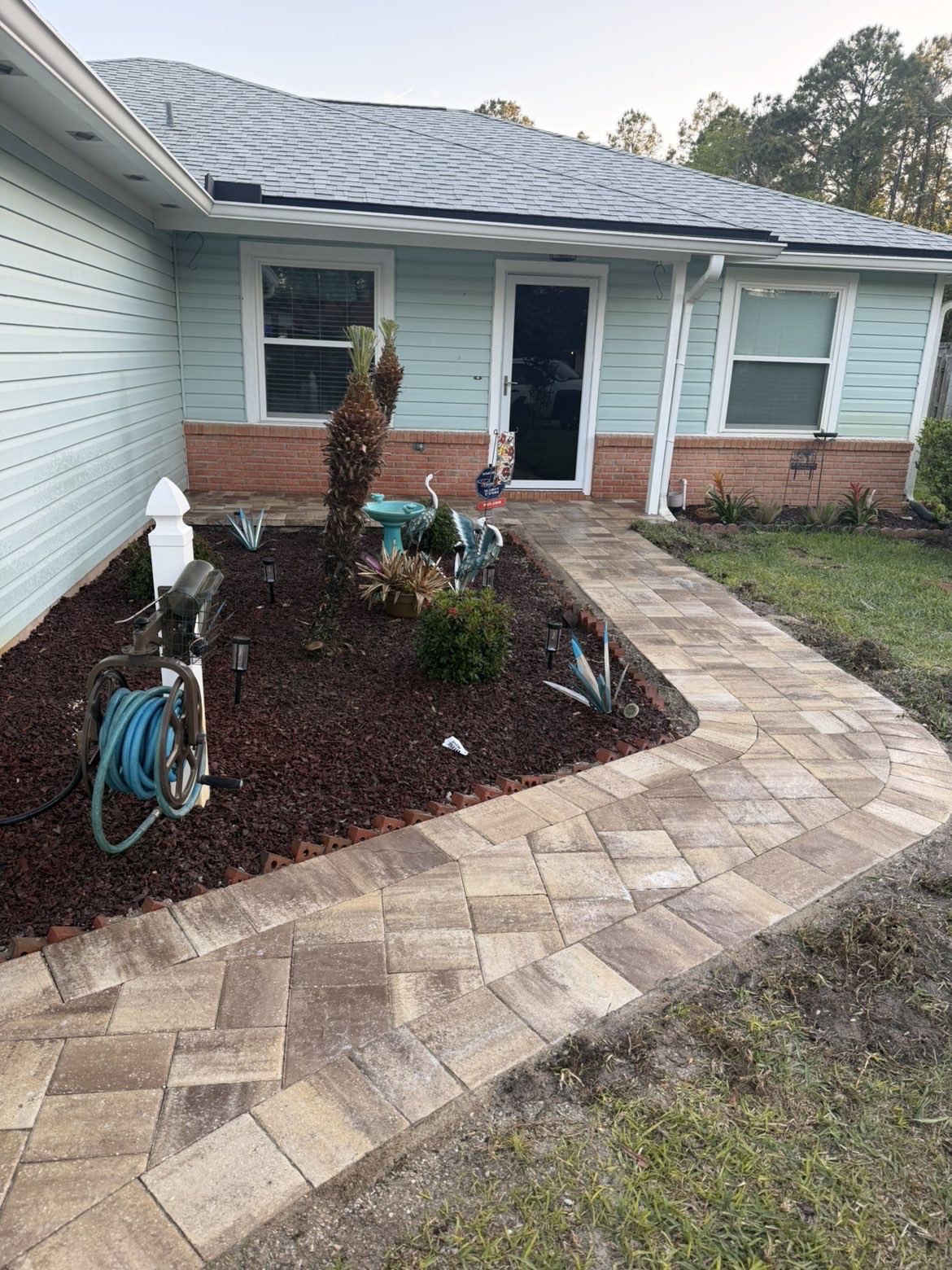 Curved paver walkway leading from driveway to front door of a home